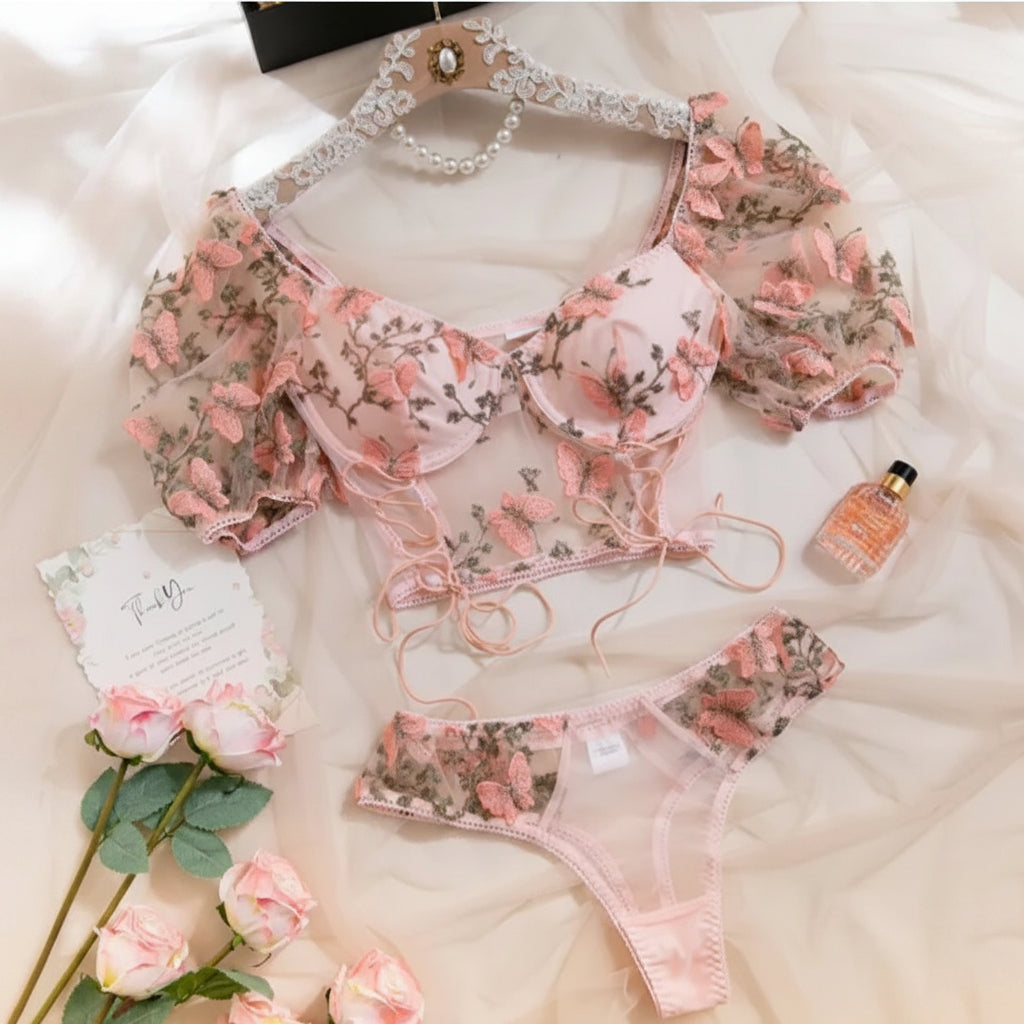 A pink floral lingerie set consisting of a sheer puff-sleeve bralette and matching knickers. 